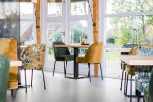 einen Tisch und Stühle in einem Zimmer mit Fenstern in der Unterkunft Hotel Bornholm in West-Terschelling