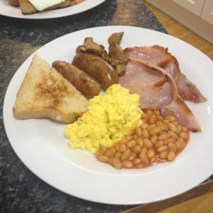 a plate of breakfast food with eggs sausage beans and toast at The Cross Guest House in Mablethorpe