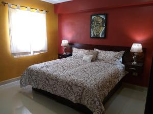a bedroom with a large bed with red walls at PRIME VILLAGE Cozumel in Cozumel