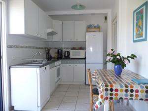 a kitchen with a table and a white refrigerator at Gîte du pré de la dame in Férel