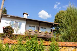 a white house with a balcony with flowers on it at Къща за гости Пъстрина in Sŭbotkovtsi