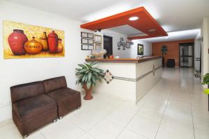 a lobby with a couch and a counter with vases on the wall at Hotel Los Tunjos in Pereira