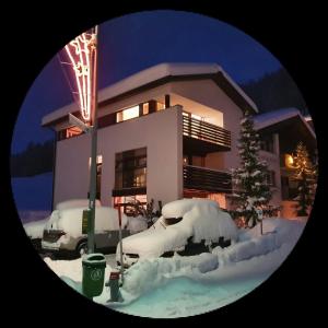 a house with snow covered cars in front of it at Chasa Miramont in Samnaun