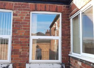 a woman standing in a window of a brick building at Beautiful 4 bedroom Victorian Apartment Sleeps 7 STOCKPORT in Manchester +5 photos