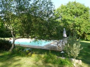 a pool with chairs and an umbrella in a yard at Les Lebes - La petite maison in Sempesserre