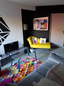 a living room with a yellow couch and a colorful rug at Au detour de Gournay in Gournay-en-Bray