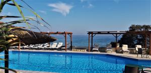 a swimming pool with chairs and the ocean in the background at Irides in Souvala
