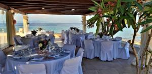 a room with white tables and chairs and the ocean at Irides in Souvala