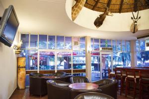 um restaurante com cadeiras pretas, uma mesa e janelas em Tshipise A Forever Resort em Tshipise