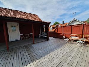 um deque de madeira com cadeiras e mesas numa casa em Gårdshotell Klockargården em Öregrund
