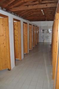 rząd drewnianych drzwi w pokoju z podłogą wyłożoną kafelkami w obiekcie Camping Pitsoni w mieście Sykia
