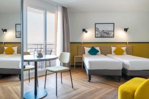 モンルージュにあるアパートホテル アダージョ パリ モンルージュのベッド2台、テーブル、窓が備わるホテルルームです。