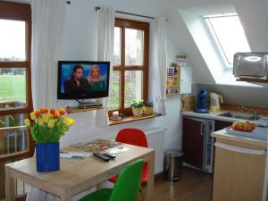 a kitchen with a table with a tv on the wall at Ferienwohnung Stockrose in Middelhagen