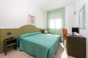 a bedroom with a bed and a desk and a computer at Hotel Sirena in Lido di Camaiore