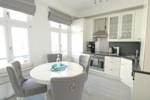 a white kitchen with a white table and chairs at WellenRausch Living "Sonnendeck" in Travemünde