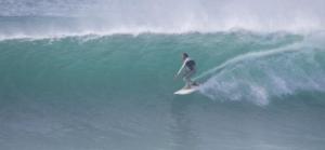 un hombre montando una ola en una tabla de surf en el océano en House BLZ en Charneca