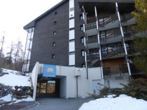 een groot gebouw met een parkeergarage in de sneeuw bij CREPUSCULE 11 in Le Sauze