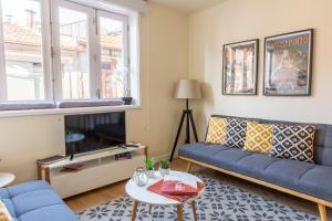 a living room with a blue couch and a tv at Oporto Between Walls by the center with A/C in Porto