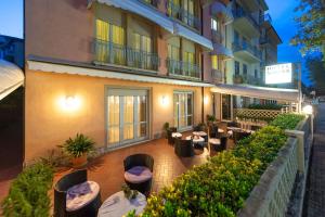 an outdoor patio with tables and chairs in front of a building at Hotel Sirena in Lido di Camaiore