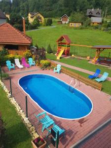 a large swimming pool with chairs and a playground at Willa i domki Victoria in Wisła