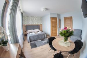 Un dormitorio con una cama y una mesa con un jarrón de flores en Willa-Wita, en Kalwaria Zebrzydowska
