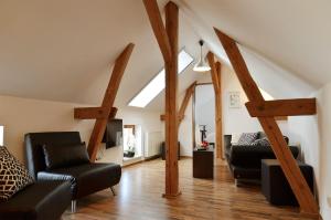 a living room with black leather furniture and wooden beams at FeWo Jung in Falkensee