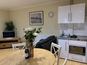 a kitchen and living room with a table with flowers on it at Southernwood - Studio 1 in Didcot