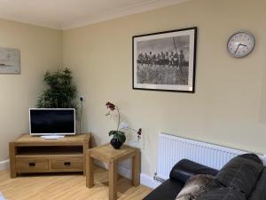 a living room with a couch and a clock on the wall at Southernwood - Studio 1 in Didcot