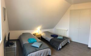 two twin beds in a attic room with blue pillows at Chambres à BINIC in Binic