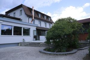 a white house with a tree in front of it at Pension Geerlisburg in Kloten