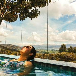 a woman in a swimming pool with a view at Bella Tierra Hotel Boutique in Tibasosa