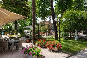 a patio with a table and chairs and flowers at Hotel Verde Luna in Cervia