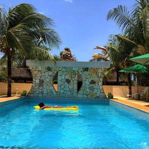 a person laying on a raft in a swimming pool at Pousada Capyvara in Arenápolis