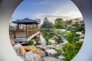 un ponte sopra uno stagno in un parco con rocce di Qing Ping Jn Humanities Hall青萍居人文會館 a Wujie