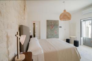 a white bedroom with a bed with a cross on it at Trulli Resort Aia Piccola in Alberobello