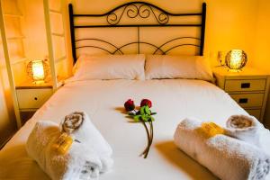 a bedroom with a bed with towels and flowers on it at Ático céntrico plaza Moravia ,San Julian. in Seville