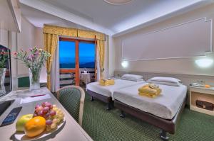 a hotel room with two beds and a table with a plate of fruit at Hotel Terme Antoniano in Montegrotto Terme