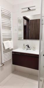 a white bathroom with a sink and a mirror at Pe-Ki Lux Apartman Székesfehérvár in Székesfehérvár