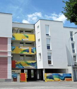 een wit gebouw met kleurrijke schilderijen erop bij 109 Apartment Bergner 4-8 Pers 68m2 in Klagenfurt