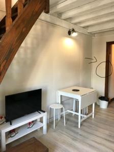 a living room with a white table and a tv at Appartement centre village in Villard-de-Lans