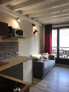 a kitchen with a couch in a room with a window at Appartement centre village in Villard-de-Lans