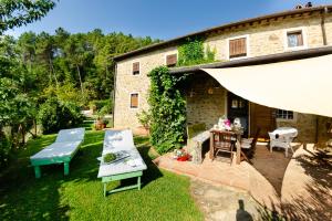 a patio with a table and chairs and a building at Podere L'Istrice in Massa e Cozzile