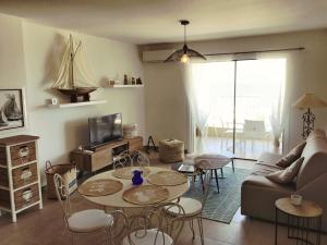 Una sala de estar con un sofá, mesas y sillas. en Domaine A Mortella T2, en Saint-Florent