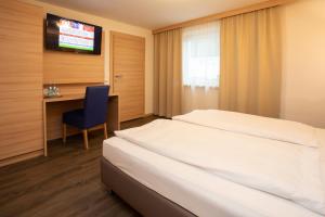 a hotel room with a bed and a desk and a television at Gasthof Rothmayr in Linz +4 photos