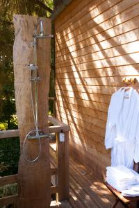 eine Dusche auf einer Holzterrasse mit einem weißen Hemd in der Unterkunft Les Cabanes de Koad'dour - séjour SPA dans les arbres in Les Portes du Coglais