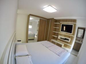 a bedroom with a white bed and a television at Apto alto padrão in Balneário Camboriú