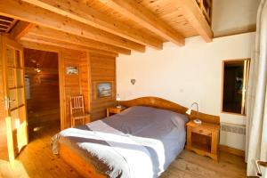 een slaapkamer met een bed in een kamer met houten wanden bij Le Troll Hameau des Chazals Nevache Hautes Alpes in Névache