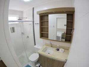 uma casa de banho com um lavatório, um chuveiro e um WC. em Apto alto padrão no Balneário Camboriú