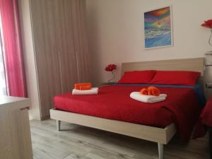 ein Schlafzimmer mit einem roten Bett mit zwei Handtüchern darauf in der Unterkunft House of colours in Alghero