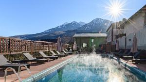 a pool with chaise lounge chairs and a mountain at HILLS POLYANA Hotel & SPA I ОТЕЛЬ ХИЛЛС ПОЛЯНА in Krasnaya Polyana